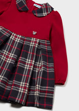 Load image into Gallery viewer, A close-up of a children's dress with a solid red long-sleeve bodice with plaid collar,and a pleated navy, red, and cream plaid skirt. A small silver heart-shaped button on the chest.