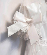 Load image into Gallery viewer, A beautiful three piece Christening outfit comprising a simple white satin gown with cap sleeves, an embroidered organza lace effect "coat" to wear over it, and a matching bonnet. The "coat"  has puff sleeves decorated with bows. It is fastened with pearl buttons and loops and is edged in guipure style lace trimming. The bonnet is fastened with velcro and is edged with a pretty organza frill. buy online on kidstuff.ie