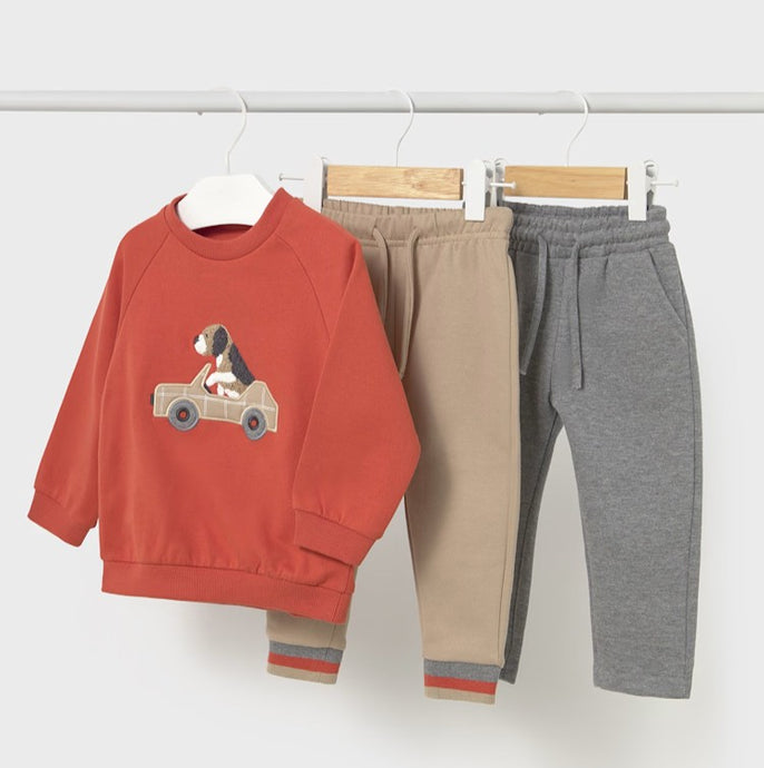 Orange sweatshirt with dog in a car design on the front plus  a pair of beige jog bottoms and a pair of grey jog bottoms. mayoral 2841 3 piece boy's tracksuit available on kidstuff.ie