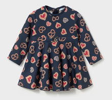 Load image into Gallery viewer, A navy blue long-sleeve dress for toddlers, featuring an all-over pattern of red and beige hearts, pretzels, etc with a small gilt buckle detail at the waist
