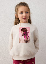 Load image into Gallery viewer, A young girl  wearing a cream-colored sweatshirt with a pink graphic print of a character,and wine coloured printed trousers.
