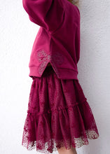 Load image into Gallery viewer, side view of Girl wearing loose raspberry red sweatshirt and a tulle tiered skirt with sparkle dtails and bow appliqué
