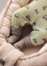 Load image into Gallery viewer, A close-up of a baby's legs wearing pale sage green quilted pants with a blue and yellow tractor pattern.
