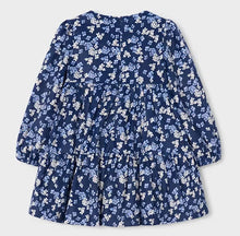 Load image into Gallery viewer, A long-sleeve tiered dress with a navy blue base and an all-over white and light blue floral print, shown against a light gray background.
