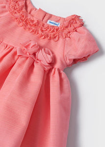 A beautiful dress for a baby or toddler girl in coral pink . High-waisted style . Short puff sleeves and neckline decorated with ruffles. Waist embellished with fabric bow two roses Net underneath. Centre back concealed zipper. Made by Mayoral