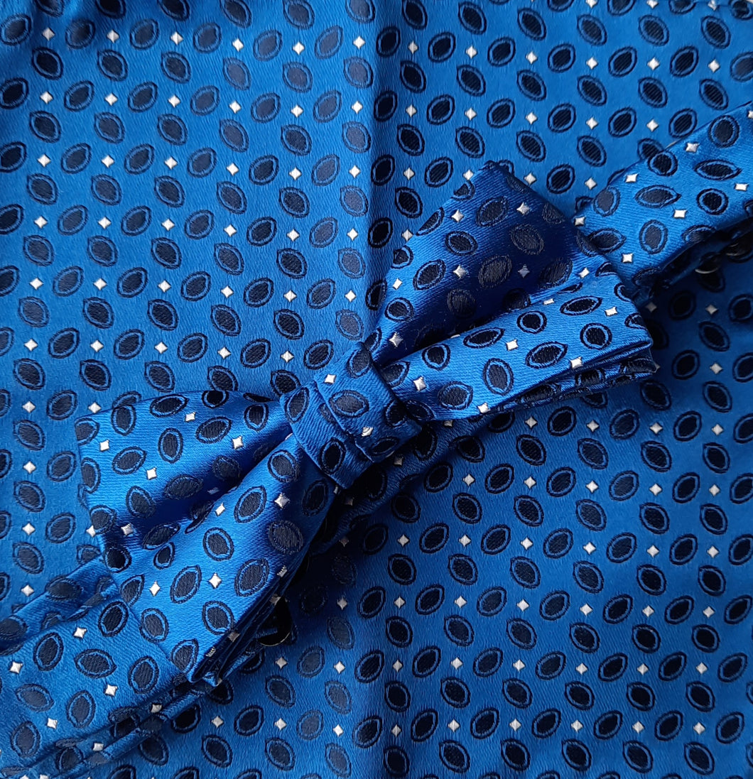Boy's bow tie and pocket square royal blue brocade patterned with black and a tiny silver grey dot. The necktie is on an adjustable band for a comfortable fit from about 7 years to 14 years and has a hook and bar fastening. Suitable for special occasions including First Communions and weddings. 