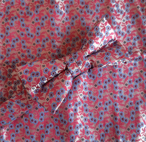 Boy's bow tie and pocket square in pink brocade patterned with tiny light blue flowers and deeper pink leaves. The necktie is on an adjustable band for a comfortable fit from about 7 years to 14 years and has a hook and bar fastening. Suitable for special occasions including First Communions and weddings