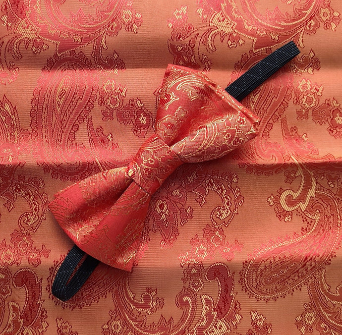 Boy's bow tie and pocket square in orange brocade patterned with an all-over paisley design. The necktie is on an elastic band for a comfortable fit from about 7 years to 10 years. The pocket square is double faced. Suitable for special occasions including First Communions and weddings